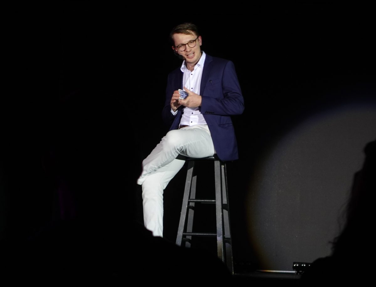 Sam King commanding the stage during a full stage magic performance, captivating an enthusiastic crowd